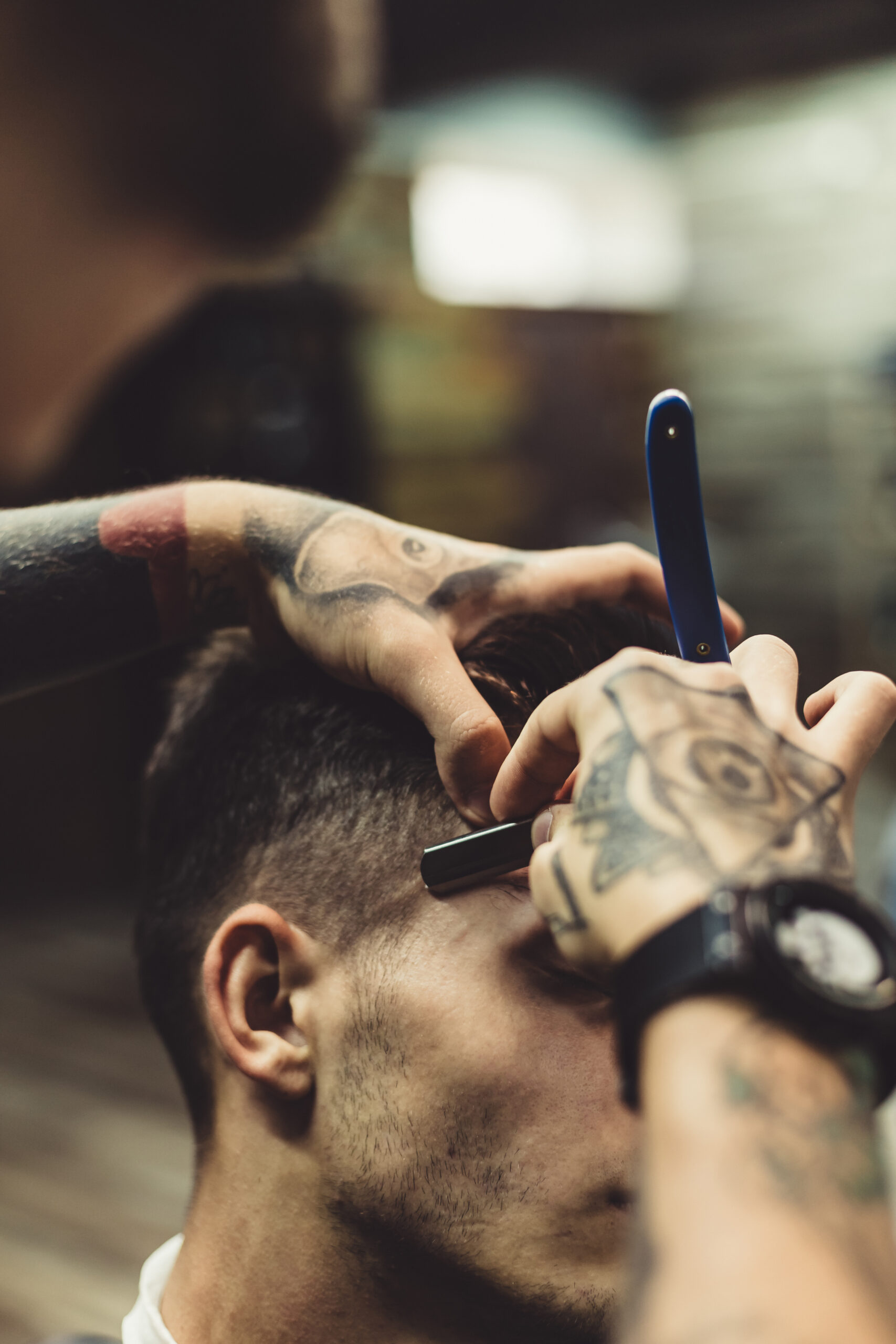 Crop stylish applying foam on customer's cheeks for shaving while working in barbershop.