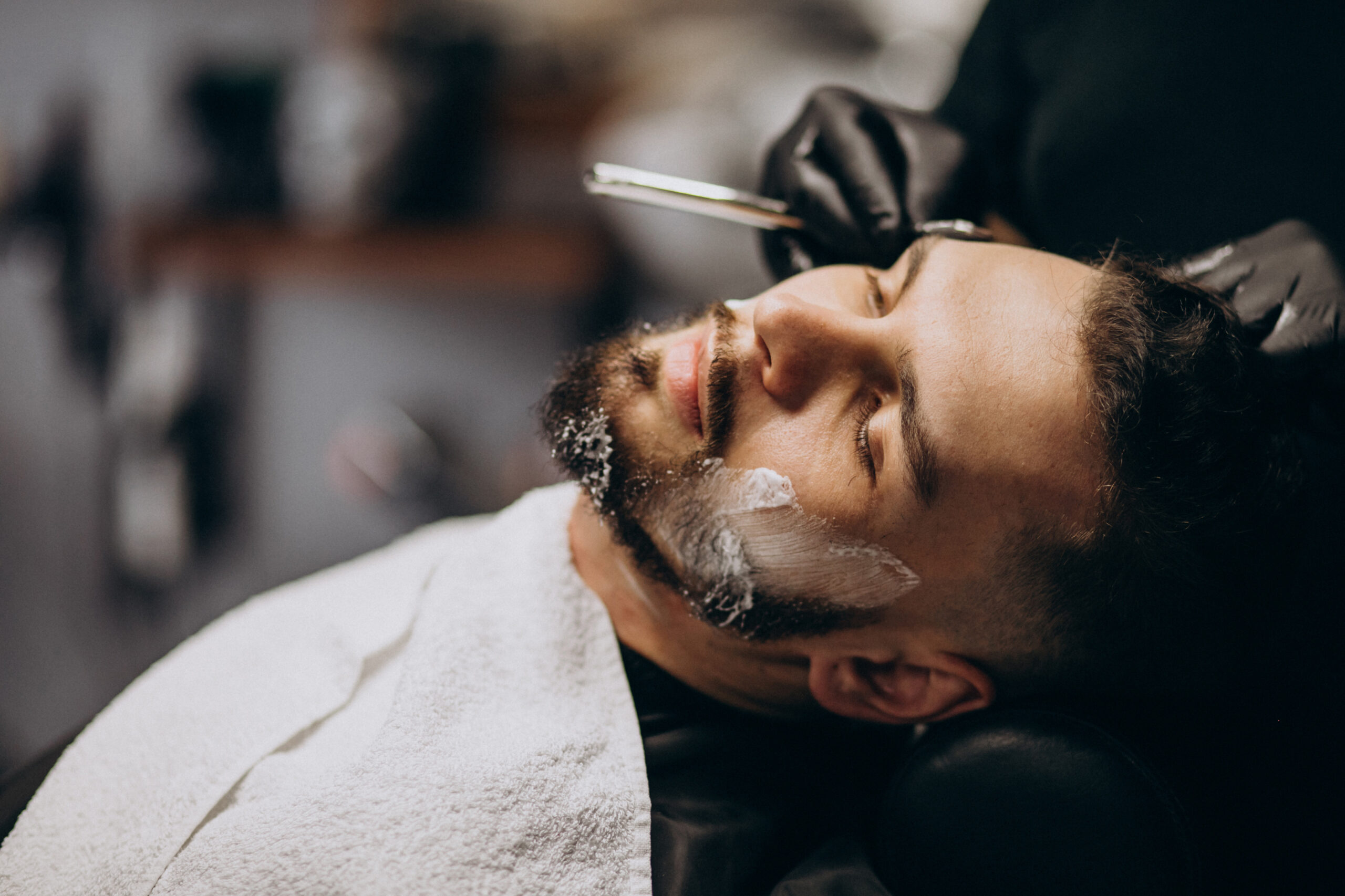 Handsome man cutting beard at a barber shop salon